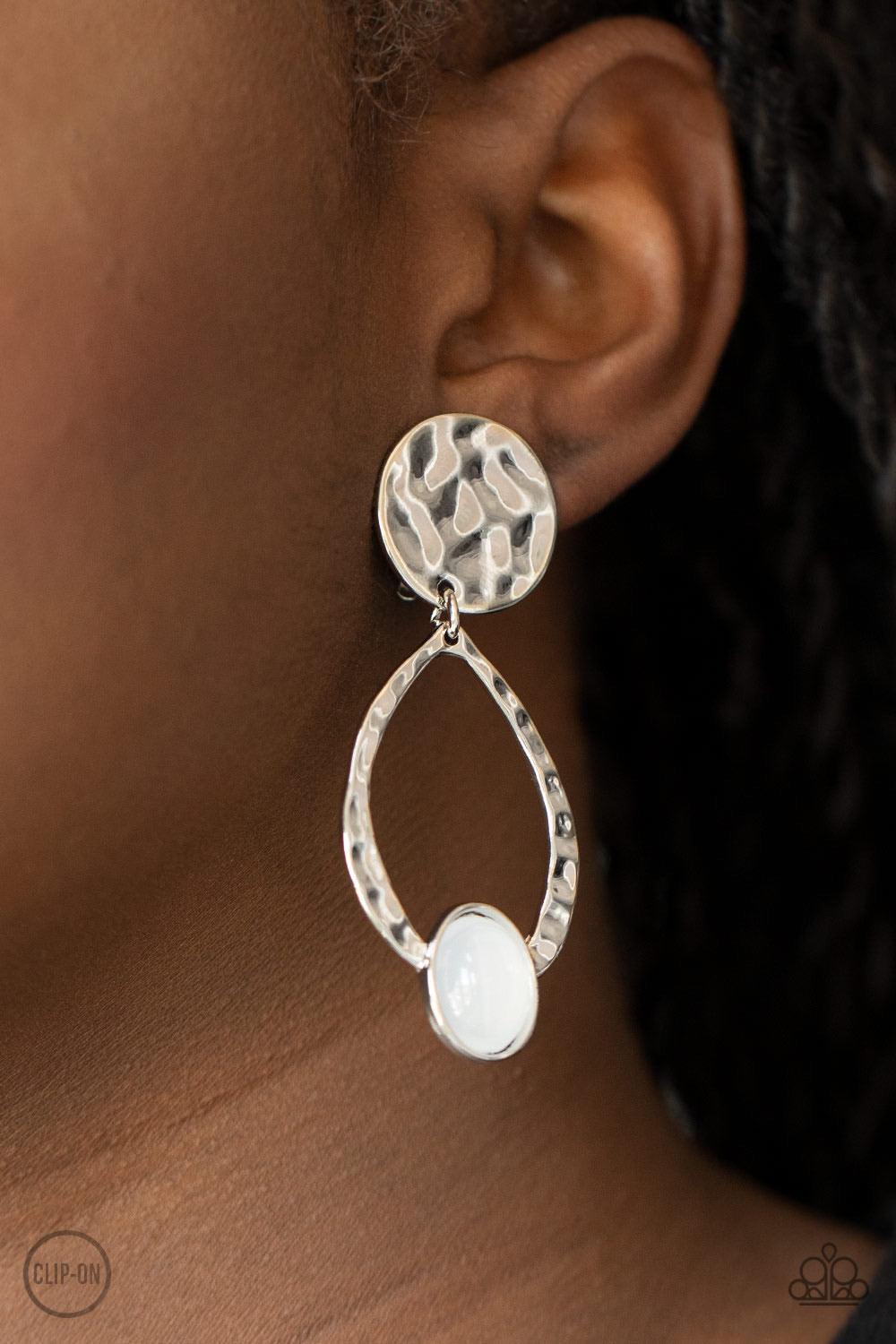 Paparazzi Accessories Opal Obsession - White *Clip-On An opalescent white cat's eye stone dots the bottom of a hammered silver frame that links to a hammered silver disc, coalescing into a dreamy lure. Earring attaches to a standard clip-on fitting. Sold
