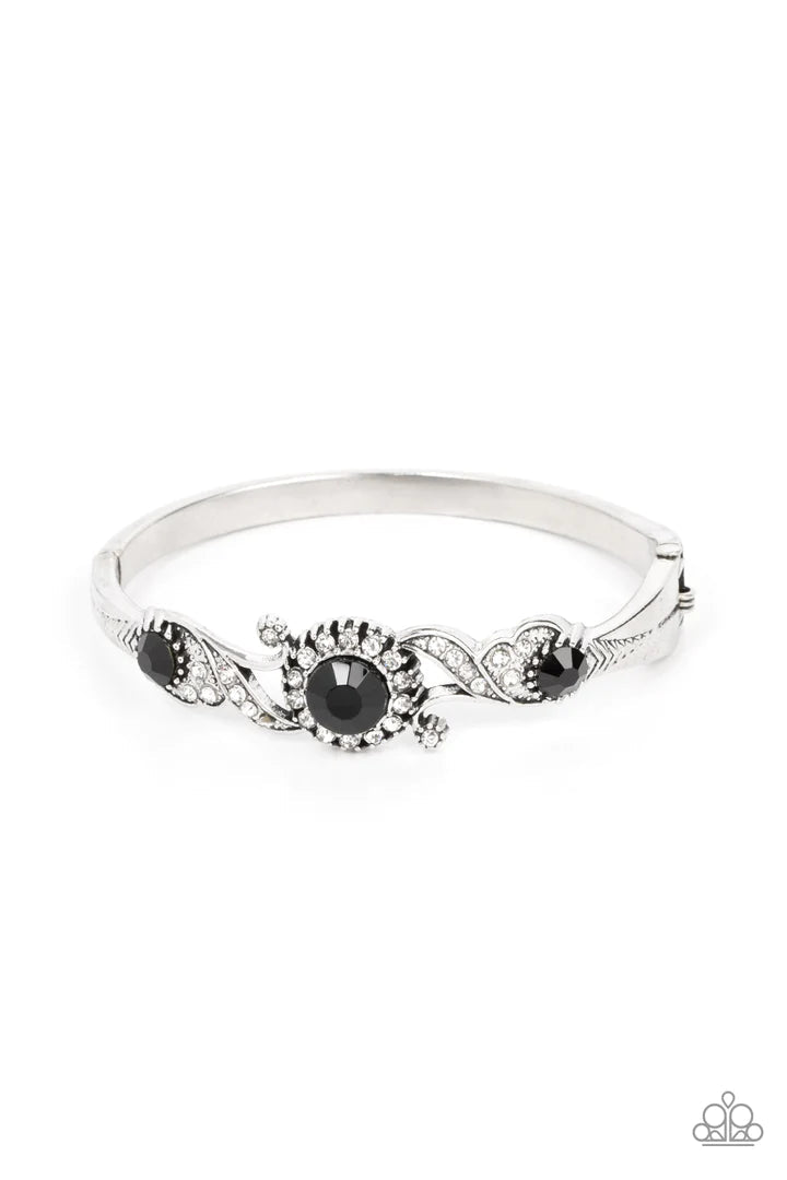 Paparazzi Accessories Expert Elegance - Black Dotted in dainty white rhinestones, leafy and floral silver frames swoop around black rhinestone centers atop a dainty silver bangle-like bracelet, resulting in an elegant centerpiece. Sold as one individual b