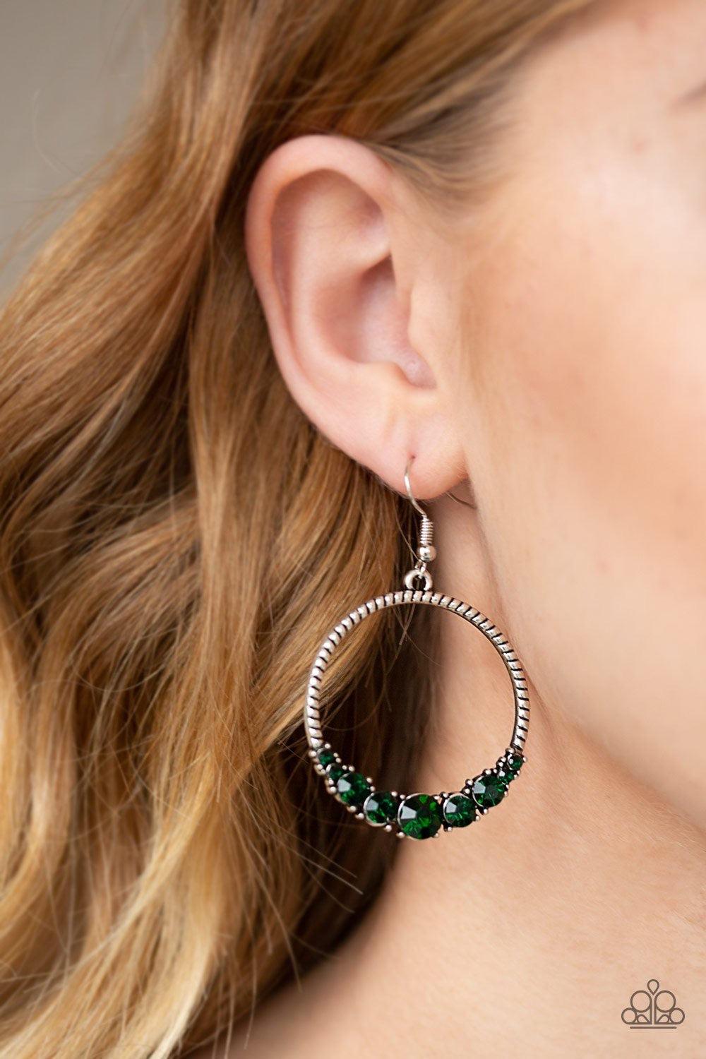 Paparazzi Accessories Self-Made Millionaire - Green The bottom of a textured silver hoop is encrusted in glittery green rhinestones for a glamorous look. Earring attaches to a standard fishhook fitting. Jewelry