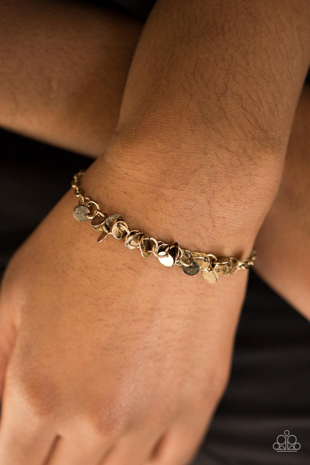Paparazzi Accessories Shimmer Train - Brass Dainty brass discs trickle along the wrist, creating a flirty fringe. The flat shiny discs catch and reflect the light, creating playful movement across the skin. Features an adjustable clasp closure. Jewelry