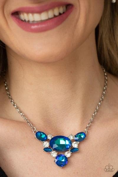 Paparazzi Accessories Cosmic Coronation - Blue Featuring a UV shimmer, oversized blue iridescent gems and glassy white rhinestones delicately coalesce into a v-shaped pendant below the collar for over-the-top glamour. Features an adjustable clasp closure.